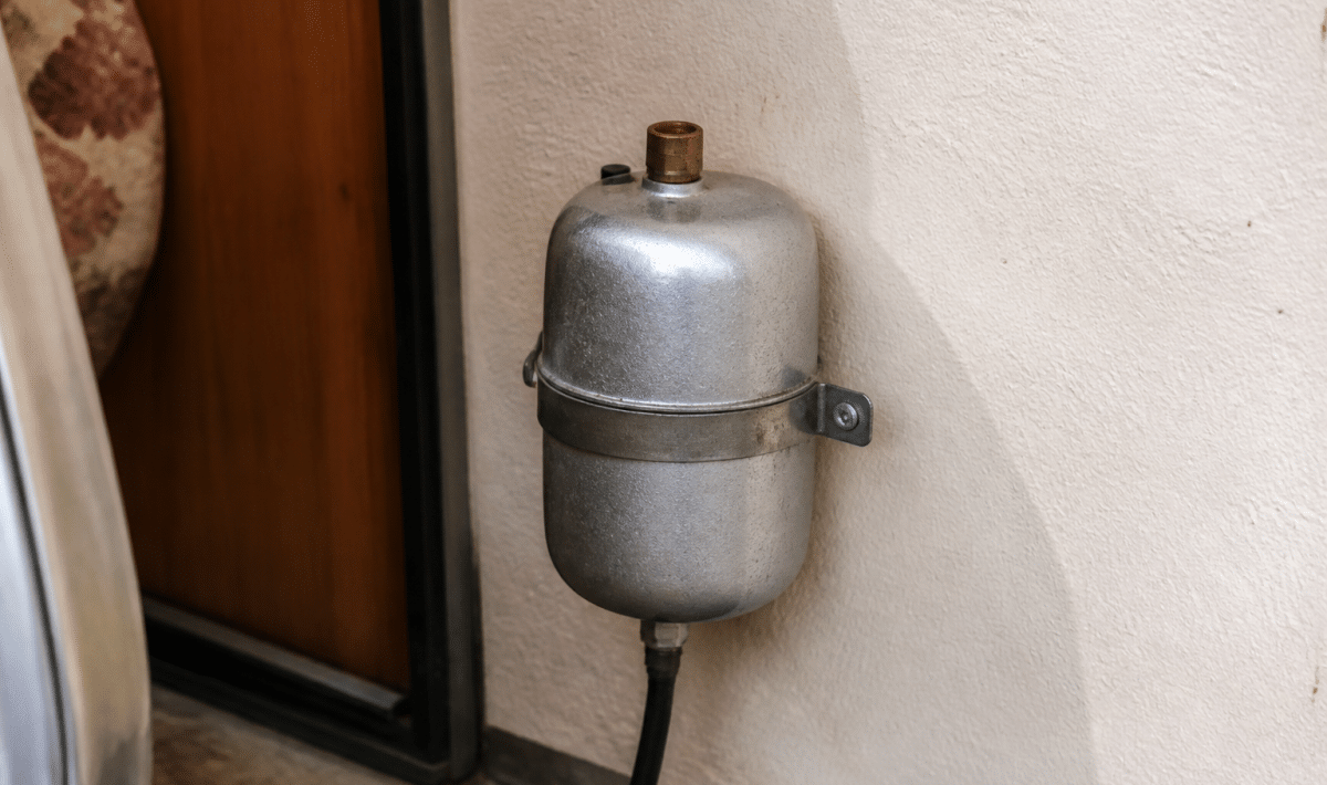 Petit reservoir metallique argente fixe contre paroi caravane