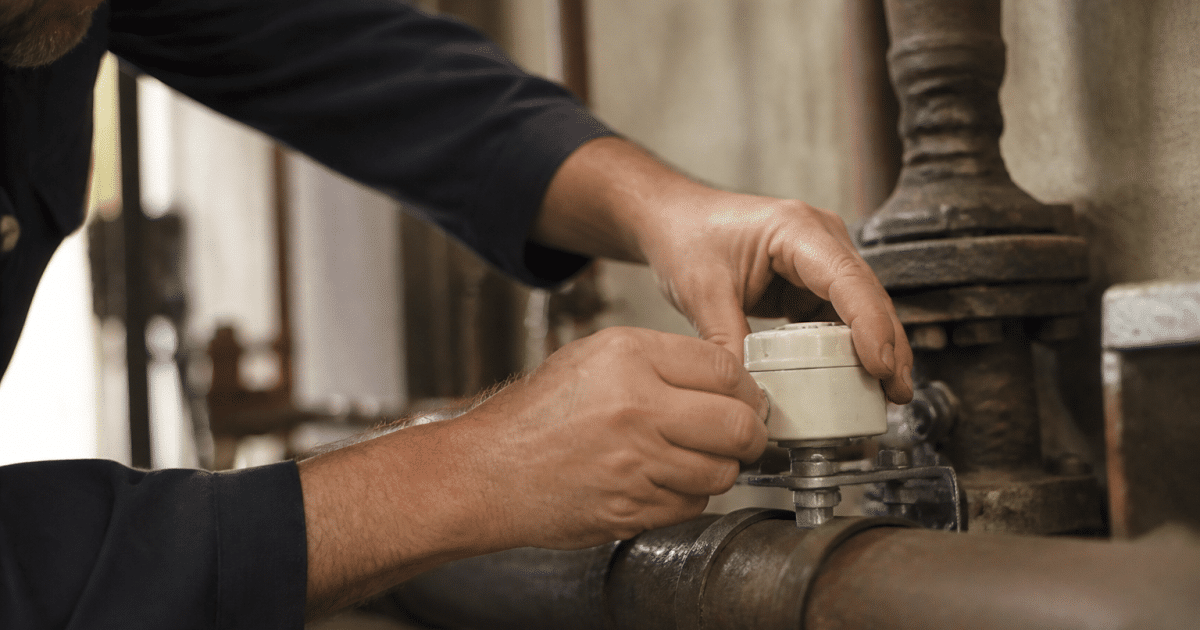 Main fixant appareil blanc sur tuyauterie metallique chaudiere