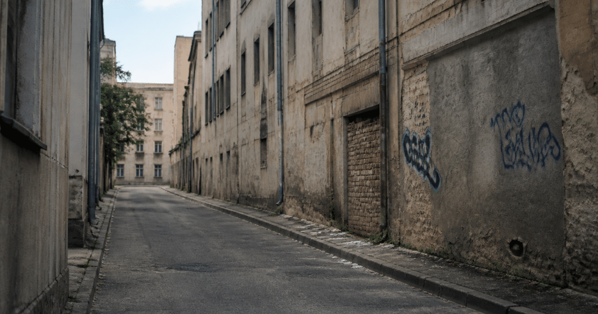 Rue urbaine déserte avec immeubles dégradés et tags muraux visibles