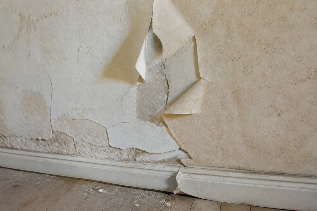 Mur poudreux fissure avec papier peint qui se decolle