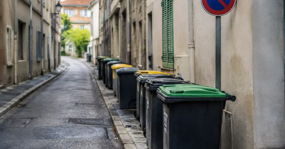 Rue etroite bordee de poubelles et panneau de stationnement